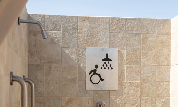 Accessible shower sign with a wheelchair symbol on a stone tile wall