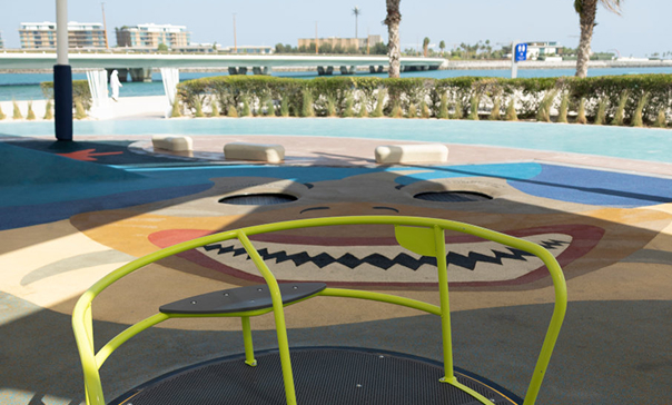 Children's playground with a colorful painted surface and a green spinning roundabout